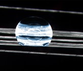 Wo Wasser nicht benetzen kann: Selbst gedehnte Fasern lassen den Wassertropfen (blau) abperlen. (Mikroskopie, 20-fache Vergrösserung) (Bild: Cilander/Empa)