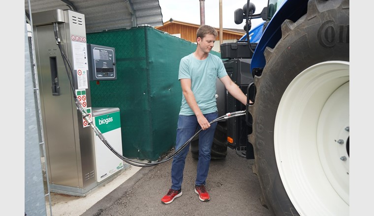 Pascal Pletscher, Mitarbeiter der Müller Energie GmbH, tankt an der hofeigenen Biogastankstelle den CNG-betriebenen Traktor. Er kann nun mit regionalem Treibstoff die Feldarbeit erledigen. (Bild: ©CNG-Mobility / Ökostrom Schweiz)