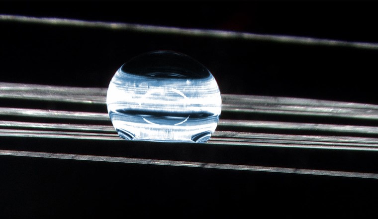 Là où l'eau ne peut pas mouiller : Même les fibres étirées font perler la goutte d'eau (en bleu). (Microscopie, agrandissement 20 fois) (Image : Cilander/Empa)