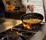 Der Koch bei der Zubereitung einer Gemüsepfanne mit frischen Produkten aus der Region Der Koch bei der Zubereitung einer Gemüsepfanne mit frischen Produkten aus der Region