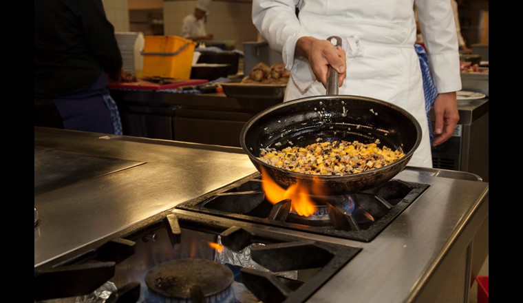 Le cuisinier en train de préparer une poêlée de l1ögumes à base de produits frais de la région