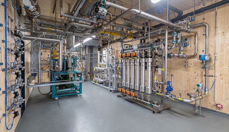 Fig. 4 Les agrégats auxiliaires de l’installation PtG: un compresseur (groupe bleu-vert à gauche) comprime le gaz d’épuration de 20 à 30 mbar à la pression requise de 7 bar avant de l’envoyer dans le bioréacteur. En aval du bioréacteur, plusieurs colonnes de charbon actif (au centre de l’image, avec en plus des colonnes placées à l’extérieur) assurent la désulfuration du biométhane. La membrane à hydrogène (6 colonnes verticales) est la dernière étape de purification avant l’injection dans le réseau de gaz. Elle est indispensable dans la mesure où, selon la réglementation actuelle, le biométhane ne doit pas contenir plus de 2% d’hydrogène. (Image: Limeco)