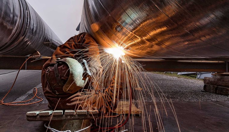 Fig. 8 Arbeiter schweisst Elemente der Transportleitung zusammen.