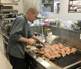 Der Koch beim Anbraten der edlen Fleischspezialitäten auf dem Gasgrill Der Koch beim Anbraten der edlen Fleischspezialitäten auf dem Gasgrill