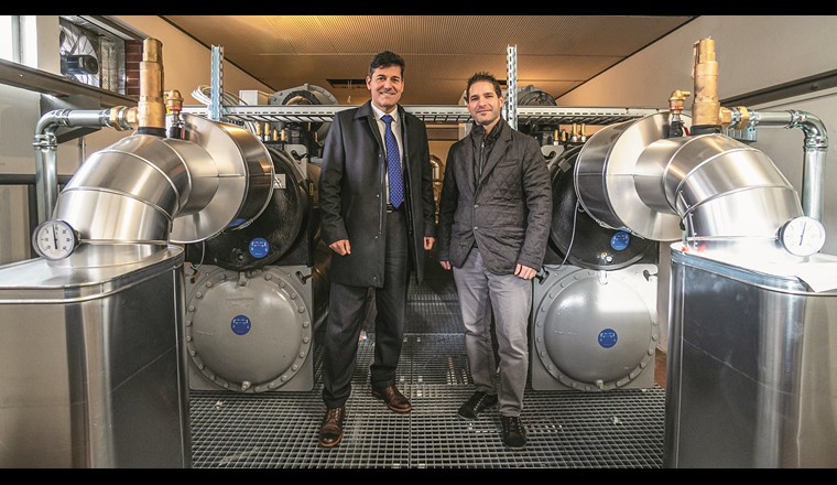 Die Heizzentrale des Wärmeverbundes bestehend aus einem Wärmetauscher, Wärmepumpe und Speicher konnte die AMB im Untergeschoss des bestehenden Pumpwerkes installieren. Direktor Mauro Suà (links) und Lorenzo Bardelli von der Azienda Multiservizi Bellinzona  (AMB) haben nach der erfolgreichen Einführung des ersten Trinkwasser-Wärmeverbundes im Tessin bereits weitere Contracting-Projekte auf dem Wärmemarkt geplant. (Foto: AMB)