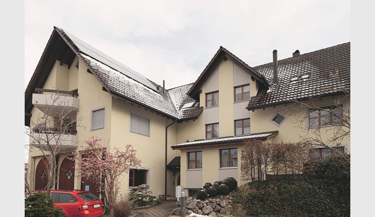 Der Hauseingang des Mehrfamilienhauses mit der
auf dem Dach installierten PV-Anlage. (Quelle Hoval AG)