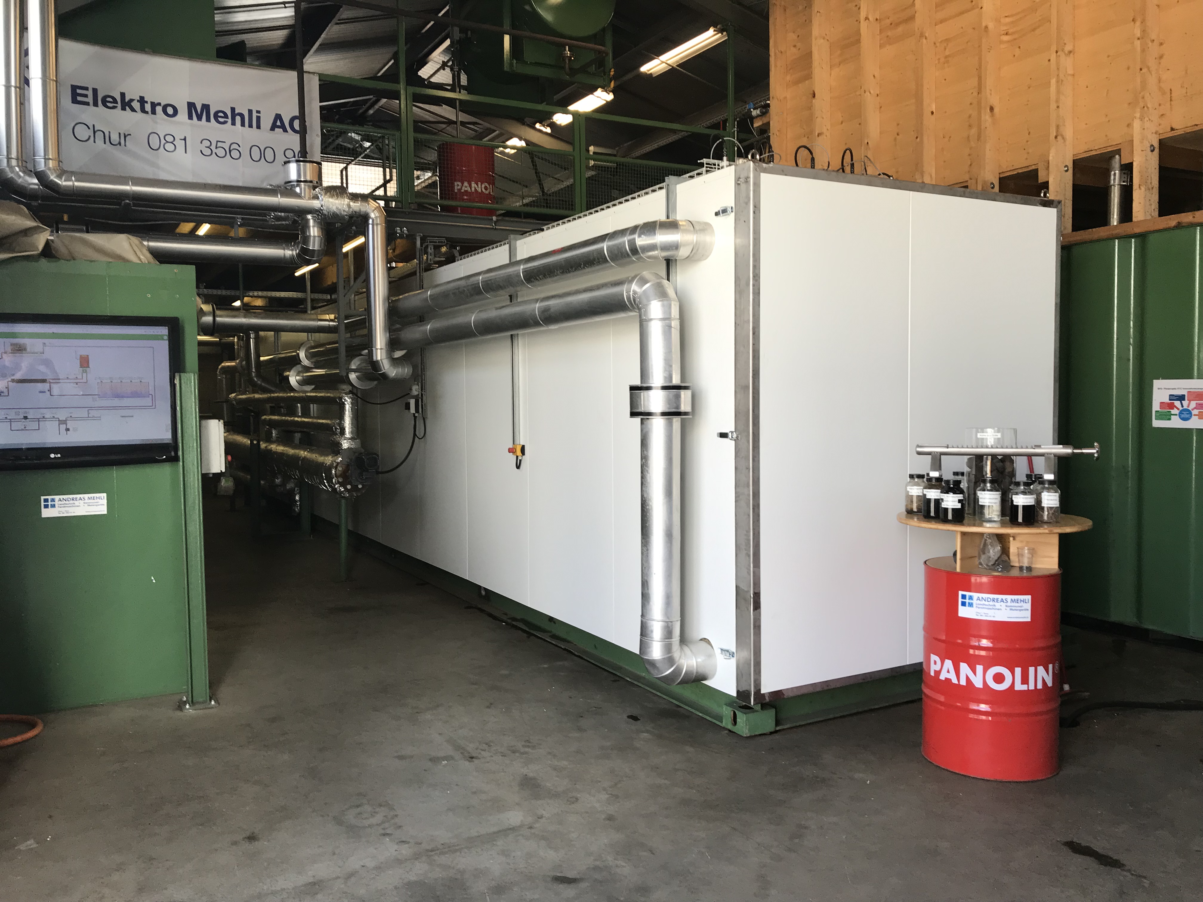 Über das isolierte vertikale Rohr im Vordergrund gelangt der auf 200 °C erhitzte und auf 20 bar komprimierte Klärschlamm in den HTC-Reaktor (weisser Container). Dort verwandelt sich der Klärschlamm in einem nur vier Stunden dauernden Prozess in Kohleschlamm, aus dessen Feststoffen anschliessend durch Pressung HTC-Kohle gewonnen wird.  (©BFE-Schlussbericht)