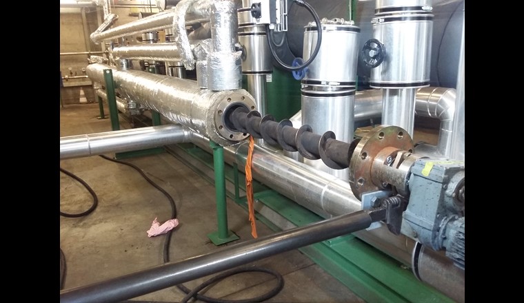 Die eigentliche Innovation der Churer Anlage ist dieses 6 m lange Rohr, in dem der Klärschlamm erhitzt und komprimiert wird, bevor er in den Reaktor gelangt. Die Erwärmung erfolgt durch 270 °C heisses Thermoöl, das im Mantel des Rohres zirkuliert. Im Innern des Rohres schiebt eine Schnecke (auf dem Foto ein Stück herausgezogen) den Klärschlamm langsam voran und sorgt zugleich dafür, dass er sich während des Erhitzens nicht an der Innenwand des Rohres festsetzt.  (©BFE-Schlussbericht)